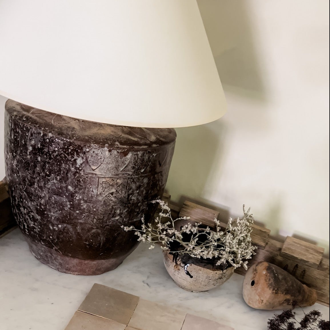 Indonesian clay safe pictured with an antique Chinese pot, lamp, and taupe Zellige tile.